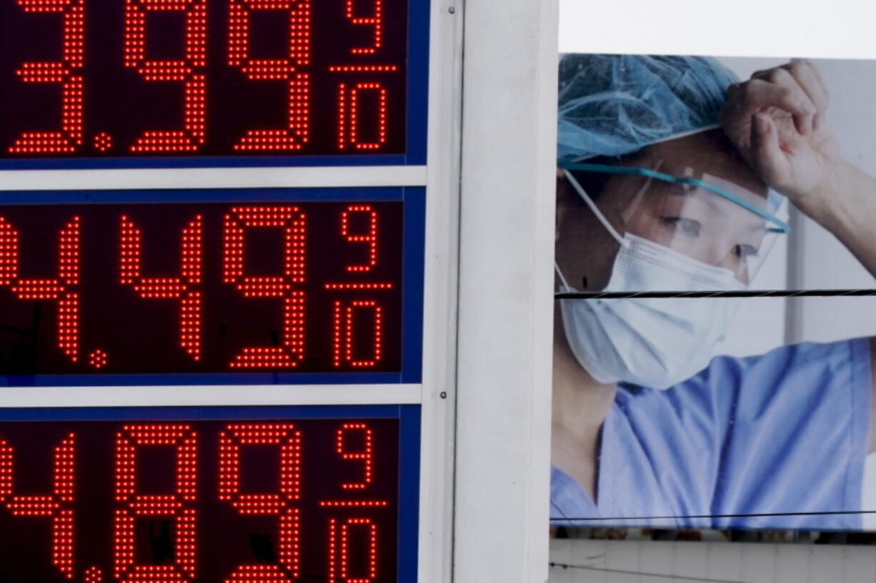 Prices are displayed on a sign at a gas station in Milwaukee on Monday with a billboard for medical services in the background.