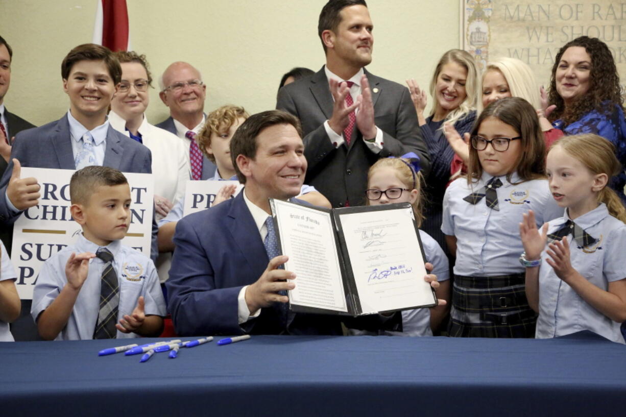 Florida Gov. Ron DeSantis displays the signed Parental Rights in Education, aka the Don't Say Gay bill, flanked by elementary school students during a news conference on Monday, March 28, 2022, at Classical Preparatory school in Shady Hills. (Douglas R.