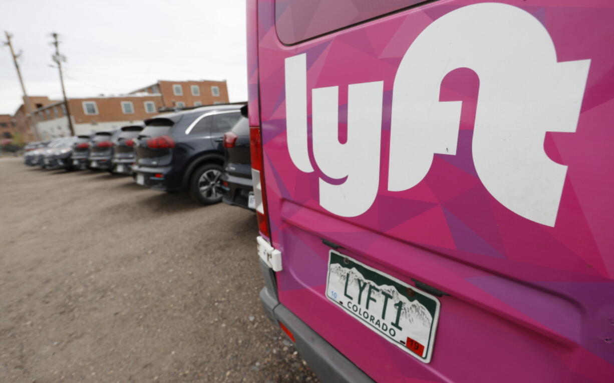 FILE - In this April 30, 2020, file photo, Kia Niros that are part of the Lyft ride-hailing fleet sit unused in a lot near Empower Field at Mile High in Denver.