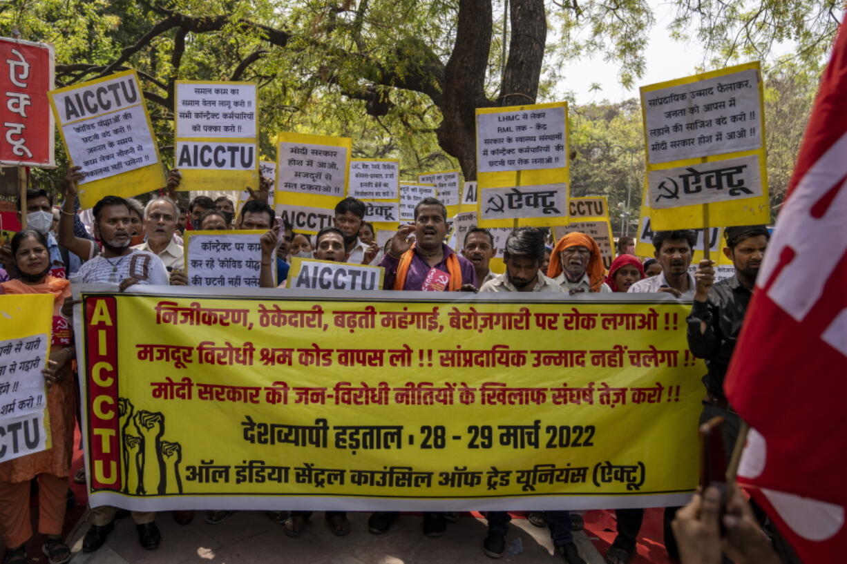 Workers and labour union activists hold placards as they march in support of a nationwide two-day strike in New Delhi, India, Tuesday, March 29, 2022. About a dozen labor unions that organized the strike want the government to provide universal social security coverage for workers in the vast unorganized sector, hike the minimum wage under a flagship employment guarantee program and scrap a new labor law that gives employers greater leeway in setting wages and working hours.