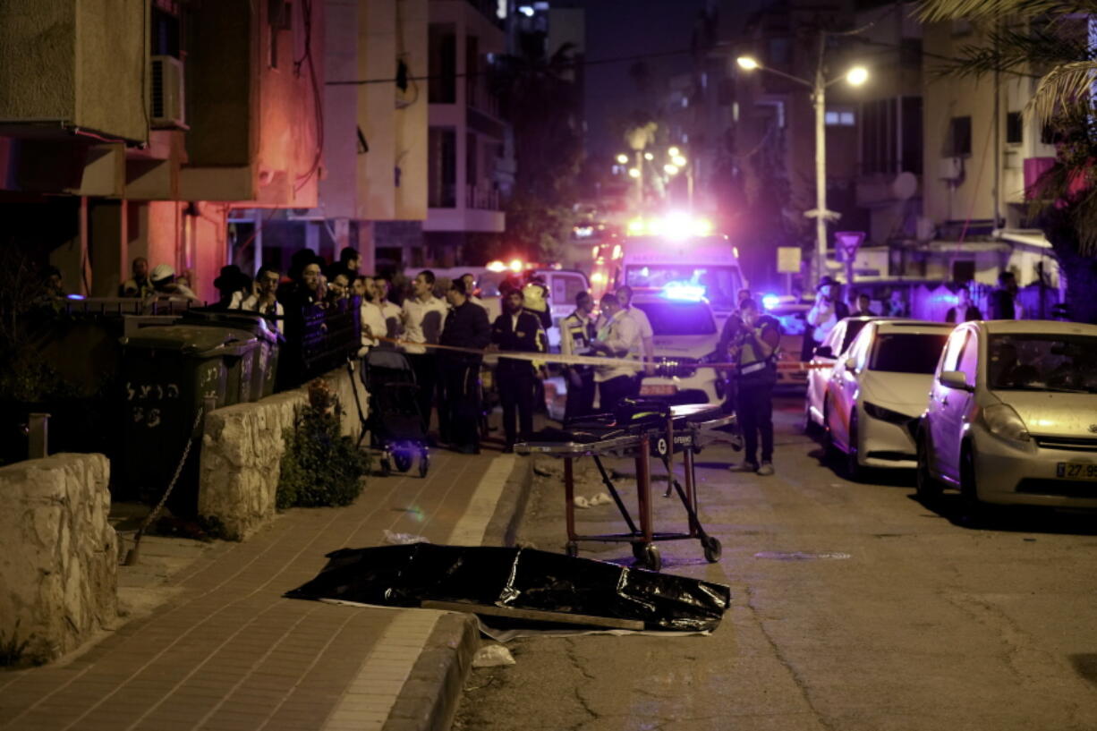 Ultra-Orthodox Jews stand near the covered body of a shooting victim in Bnei Brak, Israel, Tuesday, March 29, 2022.   The circumstance of the deadly incident Tuesday were not immediately clear.