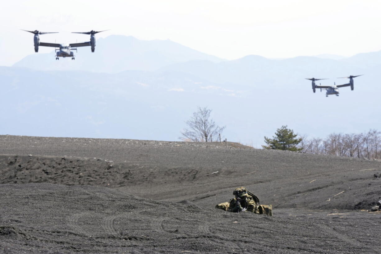 Two MV-22 Ospreys fly over as one of the members of the Japan Ground Self-Defense Force (JGSDF) guards a landing zone during a joint military drill between the JGSDF and the U.S. Marines at the Higashi Fuji range in Gotemba, southwest of Tokyo, Tuesday, March 15, 2022.