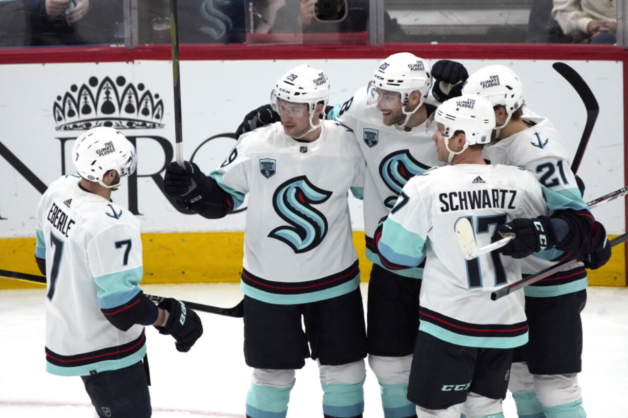 Seattle Kraken defenseman Carson Soucy, center, celebrates with right wing Jordan Eberle (7), defenseman Vince Dunn (29), center Alex Wennberg (21), and center Jaden Schwartz (17) after scoring a goal against the Arizona Coyotes during the second period of an NHL hockey game Tuesday, March 22, 2022, in Glendale, Ariz.