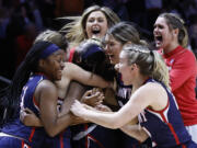 Belmont players mob Tuti Jones, center, after a double-overtime win in a college basketball game against Oregon in the first round of the NCAA Tournament, Saturday, March 19, 2022, in Knoxville, Tenn.