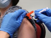 FILE - A woman receives a COVID-19 vaccine injection by a pharmacist at a clinic in Lawrence, Mass., on Wednesday, Dec. 29, 2021.   On Friday, March 11, 2022, The Associated Press reported on stories circulating online incorrectly claiming people who have received COVID-19 vaccine booster shots are at a greater risk of dying from the virus.