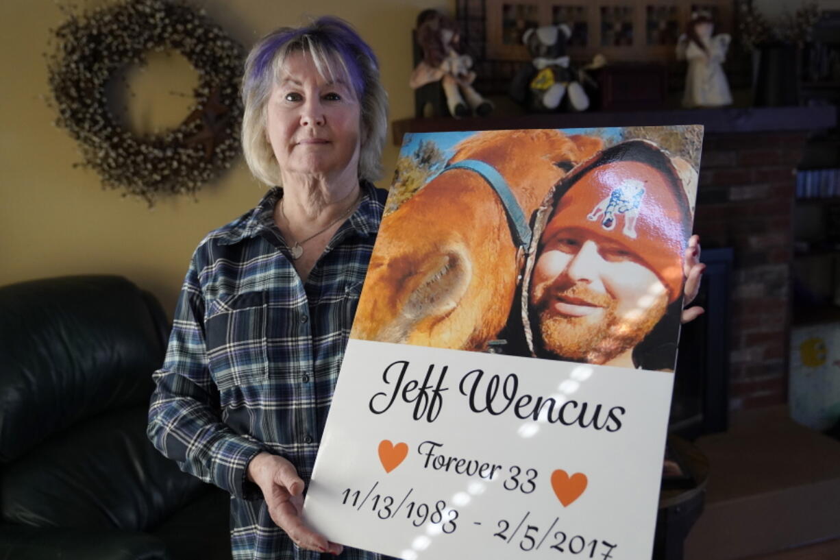 Lynn Wencus holds a poster with a likeness of her son, Jeff, on Wednesday at her home, in Wrentham, Mass. Wencus lost her son to an overdose in 2017.