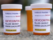 FILE - Fake pill bottles with messages about OxyContin maker Purdue Pharma are displayed during a protest outside the courthouse where the bankruptcy of the company is taking place in White Plains, N.Y., on Aug. 9, 2021. Purdue Pharma is expected to ask a federal judge Wednesday, March 9, 2022, to approve a nationwide settlement that will transform the company into a public trust and contribute up to $6 billion from members of the Sackler family, with most of the money going toward efforts to abate the nation's ongoing overdose and addiction crisis.