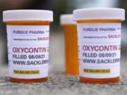 FILE - Fake pill bottles with messages about OxyContin maker Purdue Pharma are displayed during a protest outside the courthouse where the bankruptcy of the company is taking place in White Plains, N.Y., on Aug. 9, 2021. Attorney General Bob Ferguson said more than $100 million in opioid settlement money has been directed to cities and counties in Washington, including more than $33 million to Clark County.