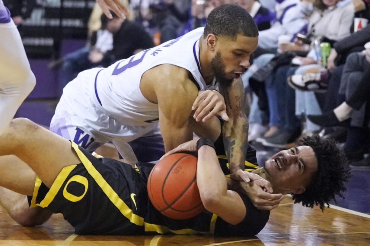 Washington guard Terrell Brown Jr., top, vies for a loose ball with Oregon guard Will Richardson, bottom, during the first half of an NCAA college basketball game Thursday, March 3, 2022, in Seattle. (AP Photo/Ted S.