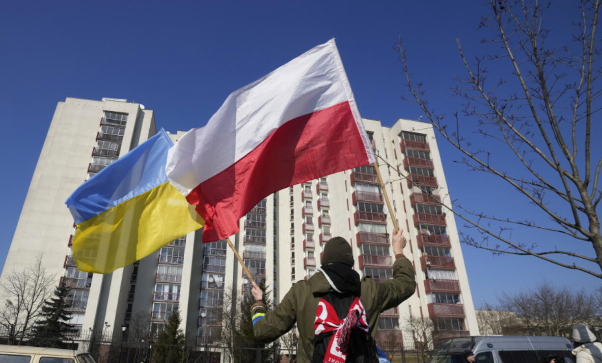 FILE - A man waves the Ukrainian and Polish flag during a demonstration in front of a building housing Russian diplomats in Warsaw, Poland, Sunday, March 13, 2022. Poland's Internal Security Agency says it has identified 45 Russian secret service officers and their associates who have enjoyed diplomatic status in Poland. The agency is asking the Foreign Ministry to expel the Russians who were described as a danger to Poland's security. The agency also said Wednesday, March 23, 2022 that it detained a Polish citizen on suspicions of espionage for the Russian secret services.