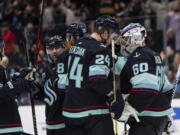 Seattle Kraken defenseman Jamie Oleksiak (24) and goalkeeper Chris Driedger (60) celebrate after the team's NHL hockey game against the Nashville Predators, Wednesday, March 2, 2022, in Seattle. The Kraken won 4-3.