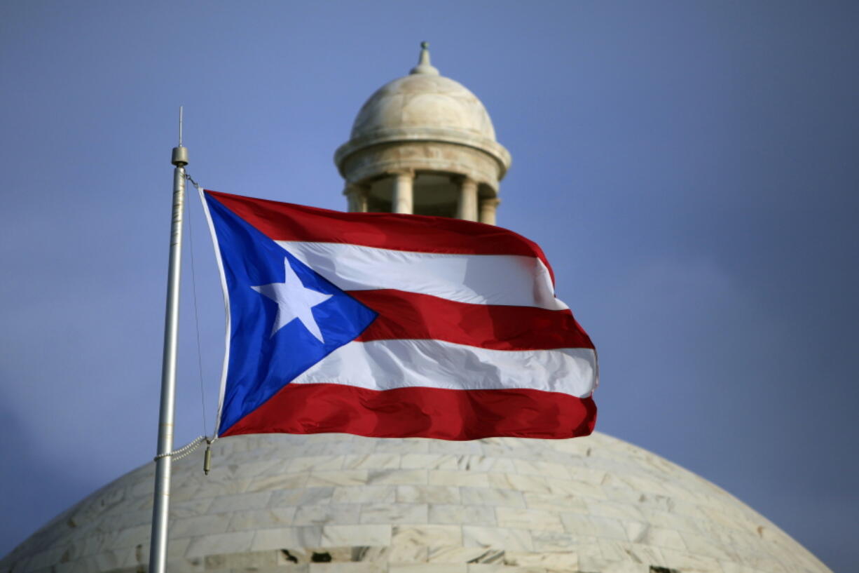 FILE - In this July 29, 2015 file photo, the Puerto Rican flag flies in front of Puerto Rico's Capitol as in San Juan, Puerto Rico. Puerto Rico's government formally exited bankruptcy Tuesday, March 14, 2022, completing the largest public debt restructuring in U.S. history after announcing nearly seven years ago that it was unable to pay its more than $70 billion debt.