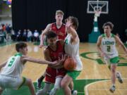 R.A. Long's Cavin Holden, center, drives to the basket as Lynden's Coston Parcher, left,, and Cemeron Petersen defend during a Class 2A state semifinal boys basketball game on Friday, March 4, 2022 in Yakima.