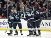 Seattle Kraken center Yanni Gourde, second from left, celebrates with center Jaden Schwartz, left, defenseman Jeremy Lauzon (55) and others after scoring the first of his two goals against the Detroit Red Wings during the third period of an NHL Hockey game Saturday, March 19, 2022, in Seattle. The Kraken won 4-2.
