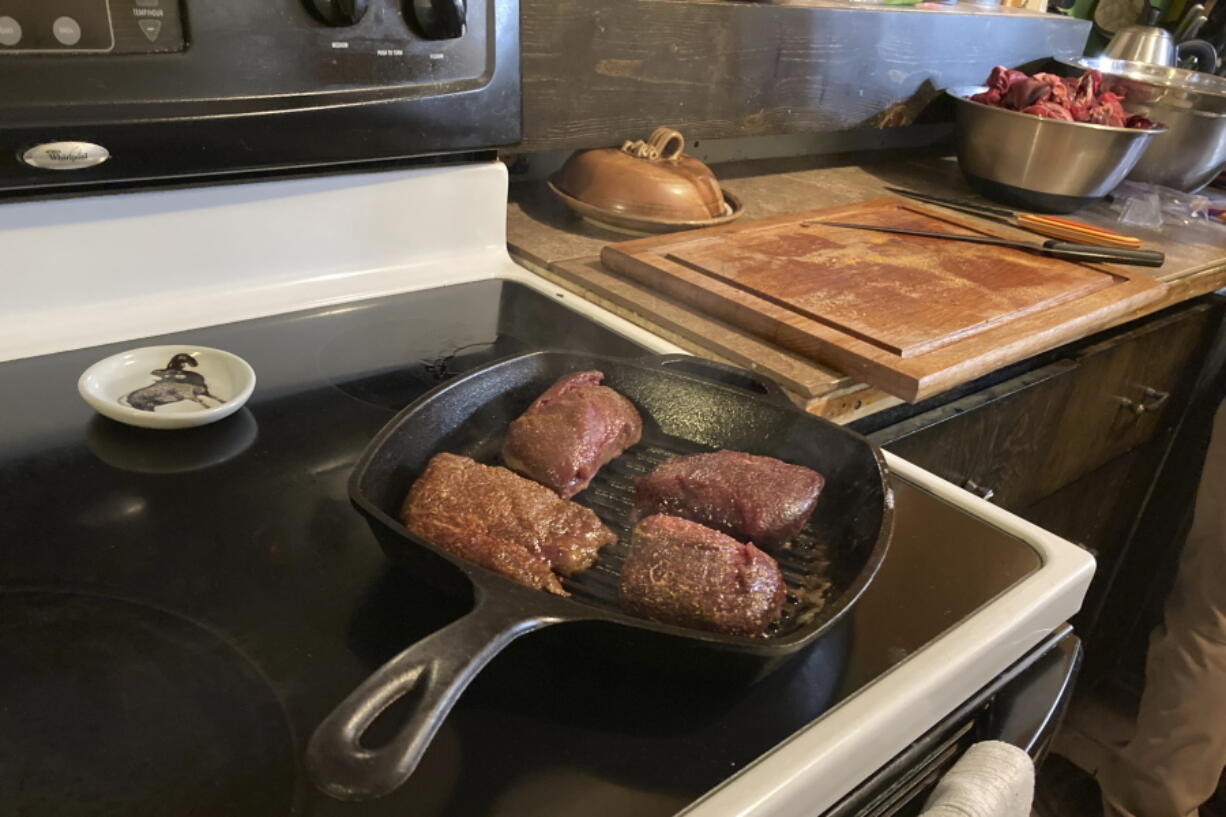 Mule deer backstrap steaks are seen cooking in Jaden Bales' kitchen south of Lander, Wyoming, on Thursday, March 3, 2022. Bales collected the deer after Lander resident Marta Casey accidentally hit it with her car. Bales used a new state of Wyoming mobile app for claiming road-killed animals to eat. The app may be the first of its kind in the U.S.