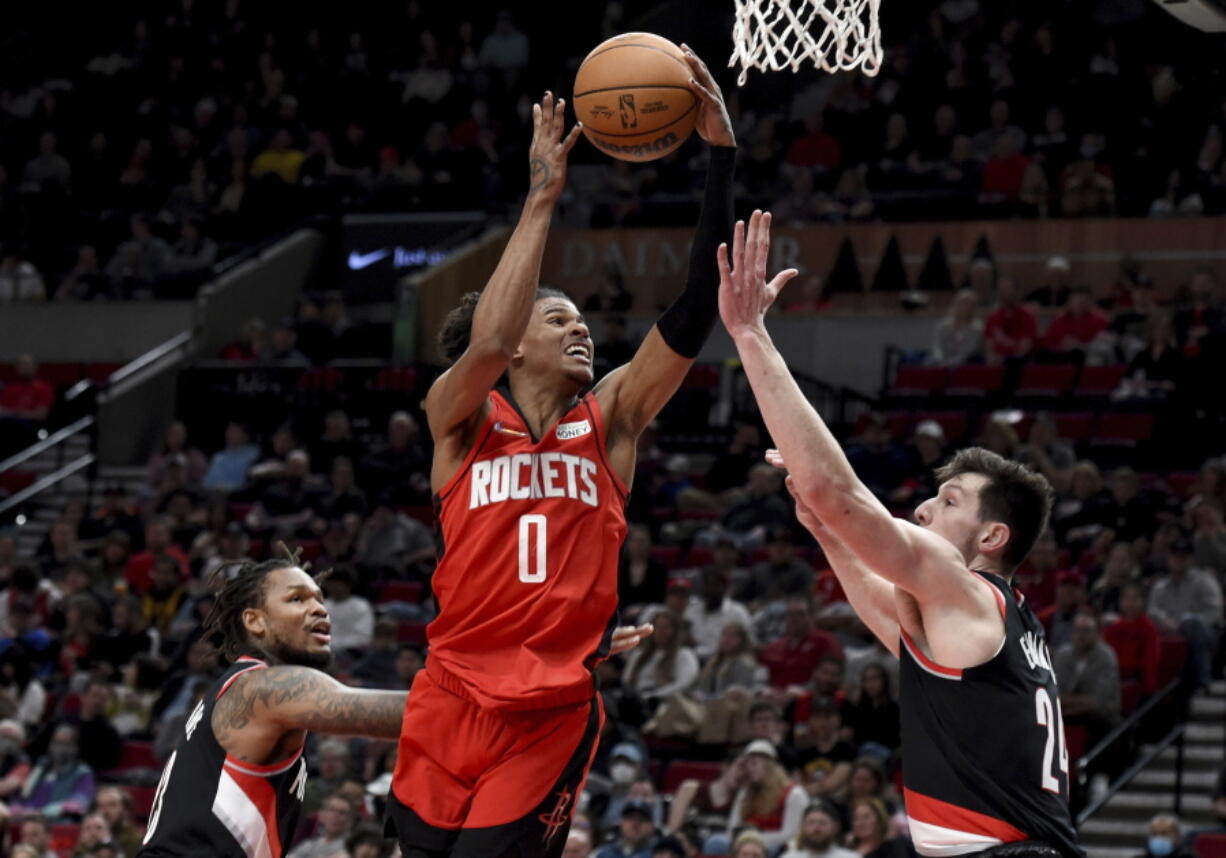 Houston Rockets guard Jalen Green, center, drives to the basket as Portland Trail Blazers guard Ben McLemore, left, and forward Drew Eubanks defend during the first half of an NBA basketball game in Portland, Ore., Saturday, March 26, 2022.(AP Photo/Steve Dykes)