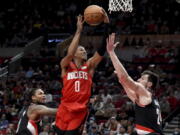 Houston Rockets guard Jalen Green, center, drives to the basket as Portland Trail Blazers guard Ben McLemore, left, and forward Drew Eubanks defend during the first half of an NBA basketball game in Portland, Ore., Saturday, March 26, 2022.(AP Photo/Steve Dykes)