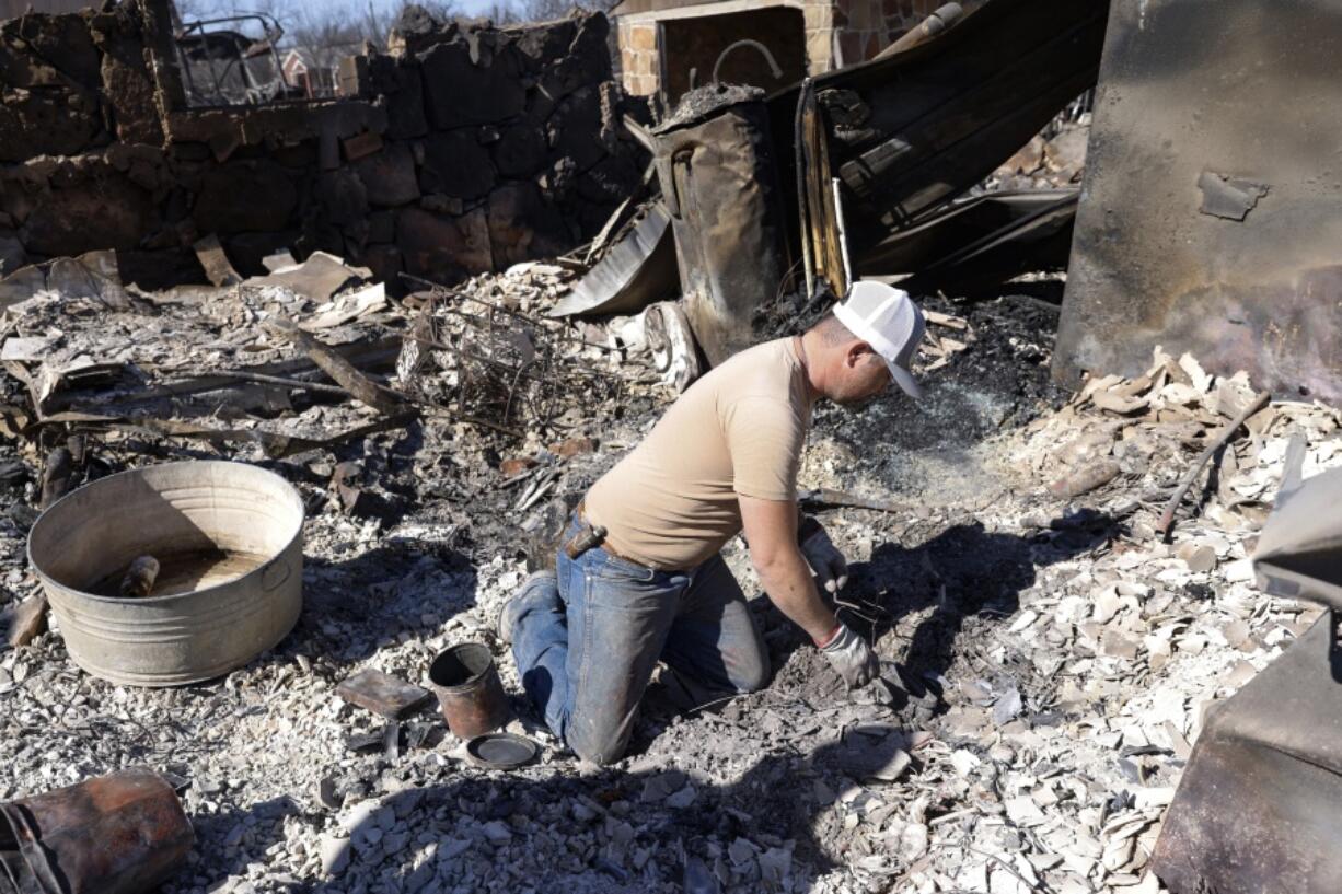 Seth Griffin sorts through the ashes of his mother's home searching for coins they collected together on Saturday, March 19, 2022, in Carbon, Texas, following the Eastland Complex Fire.