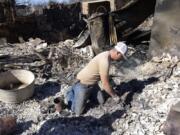 Seth Griffin sorts through the ashes of his mother's home searching for coins they collected together on Saturday, March 19, 2022, in Carbon, Texas, following the Eastland Complex Fire.