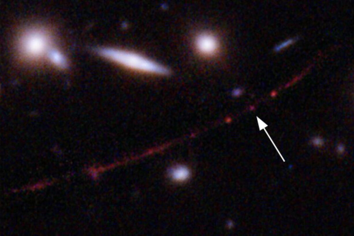 This image made available by NASA on Wednesday, March 30, 2022, shows the star Earendel, indicated by arrow, and the Sunrise Arc galaxy, stretching from lower left to upper right, optically bent due to a massive galaxy cluster between it and the Hubble Space Telescope which captured the light. The mass of the galaxy cluster serves as a magnifying glass, allowing Earendel to be seen.