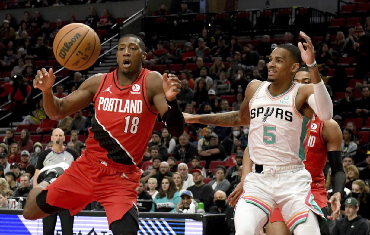 Portland Trail Blazers guard Kris Dunn, left, and San Antonio Spurs guard Dejounte Murray go after a rebound during the first half of an NBA basketball game in Portland, Ore., Wednesday, March 23, 2022.