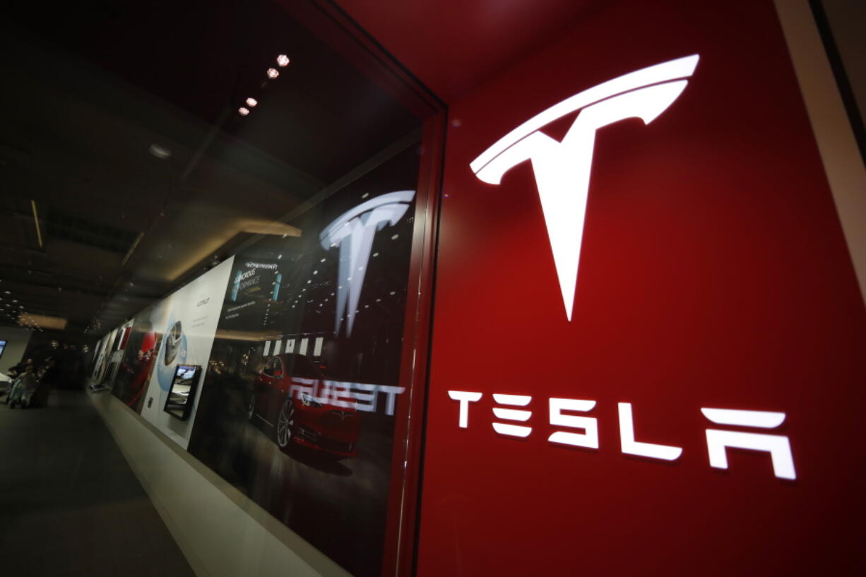 FILE - A sign bearing the company logo outside a Tesla store in Cherry Creek Mall in Denver, Feb. 9, 2019. Tesla is looking to split its stock so that the electric vehicle maker can pay a dividend to its shareholders. The company said in a regulatory filing that it plans to make a request at its upcoming annual shareholders meeting to increase its number of authorized shares so that it can split the stock in the form of a dividend.