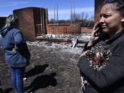 Priscilla Maynard holds a chicken while taking on the phone in front of a burned home Friday, March 18, 2022 near Carbon, Texas in Eastland County.  Fire crews in West Texas hope to make progress Saturday against a massive complex of wildfires that have killed one person and burned at least 50 homes, officials said.   (Ronald W.