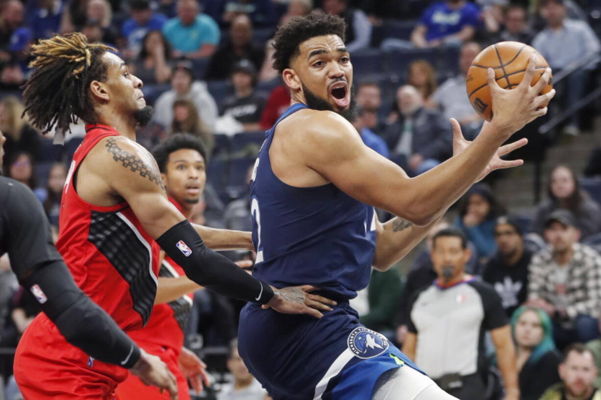 Minnesota Timberwolves center Karl-Anthony Towns, right, goes to the basket around Portland Trail Blazers forward Greg Brown III in the first quarter of an NBA basketball game Monday, March 7, 2022, in Minneapolis.