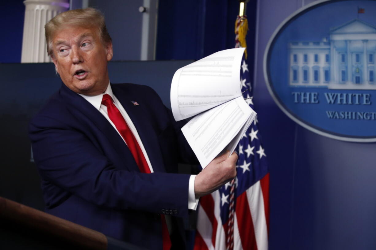 FILE - President Donald Trump holds up papers as he speaks about the coronavirus in the James Brady Press Briefing Room of the White House on April 20, 2020, in Washington. Revelations of a roughly eight-hour gap in official records of then-President Donald Trump's phone calls on the day of last year's insurrection at the U.S. Capitol are raising fresh questions about the diligence -- or lack thereof -- of the White House's record-keeping.