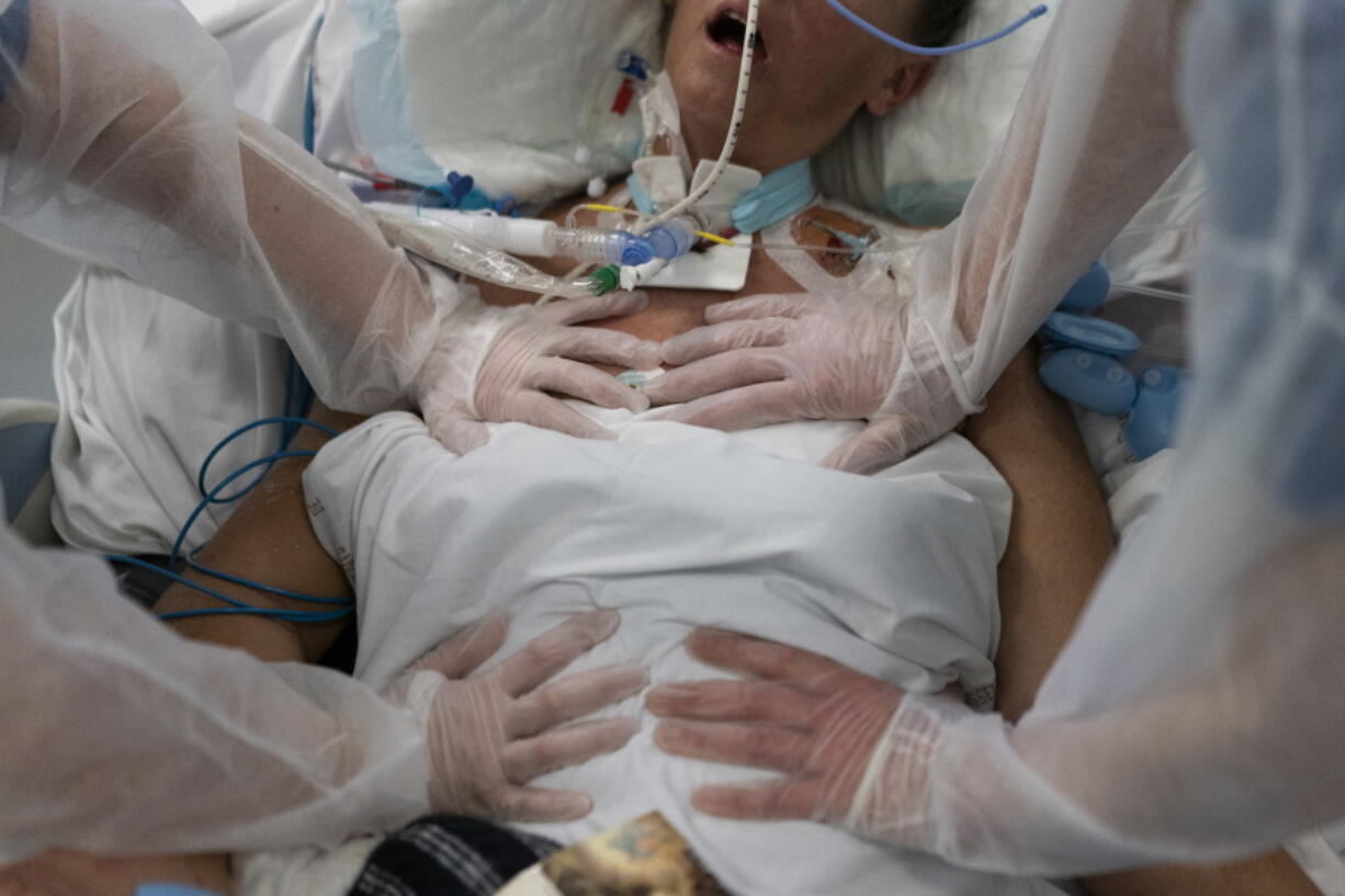 FILE - Nurses perform timed breathing exercises on a COVID-19 patient on a ventilator in the COVID-19 intensive care unit at the la Timone hospital in Marseille, southern France, Friday, Dec. 31, 2021. The official global death toll from COVID-19 is on the verge of eclipsing 6 million -- underscoring that the pandemic, now in its third year, is far from over.