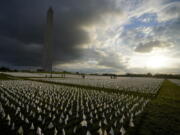 FILE - With the Washington Monument in the background, people look at white flags that are part of artist Suzanne Brennan Firstenberg's temporary art installation, "In America: Remember," in remembrance of Americans who have died of COVID-19, on the National Mall in Washington, Sept. 17, 2021. The installation consists of more than 630,000 flags. The federal government has provided more than $2 billion to help cover funeral costs for more than 300,000 families of people who died from COVID-19, the Federal Emergency Management Agency announced Tuesday as launches a new campaign to raise awareness for the aid to the families of the more than 965,000 people who have died in the U.S. from the virus.