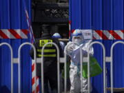 A health worker wearing a protective suit holds check lists as they walk out from a barricaded community which was locked down for health monitoring following the COVID-19 case detected in the area, Monday, March 28, 2022, in Beijing. China began its largest lockdown in two years Monday to conduct mass testing and control a growing outbreak in its largest city of Shanghai as questions are raised about the economic toll of the nation's "zero-COVID" strategy.