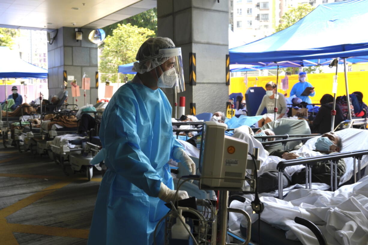 Patients in hospital beds wait in a temporary holding area outside Caritas Medical Centre in Hong Kong , Wednesday, March 2, 2022. Some people are forced to wait outside the hospital due to it currently being overloaded with possible COVID-infected patients.