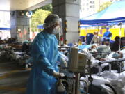 Patients in hospital beds wait in a temporary holding area outside Caritas Medical Centre in Hong Kong , Wednesday, March 2, 2022. Some people are forced to wait outside the hospital due to it currently being overloaded with possible COVID-infected patients.