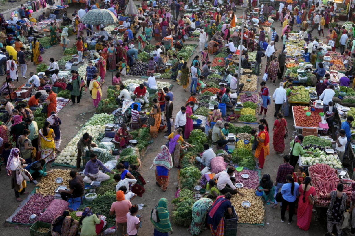 Shoppers buy produce at an open air market in Ahmedabad, India, Thursday, March 3, 2022. Slowly but steadily, life in South Asia is returning to normal, and people hope the worst of the COVID-19 pandemic is behind them. Experts are optimistic that the omicron surge, which brought relatively low levels of death, has reinforced immunity from vaccines, which are widespread in the region.