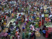 Shoppers buy produce at an open air market in Ahmedabad, India, Thursday, March 3, 2022. Slowly but steadily, life in South Asia is returning to normal, and people hope the worst of the COVID-19 pandemic is behind them. Experts are optimistic that the omicron surge, which brought relatively low levels of death, has reinforced immunity from vaccines, which are widespread in the region.