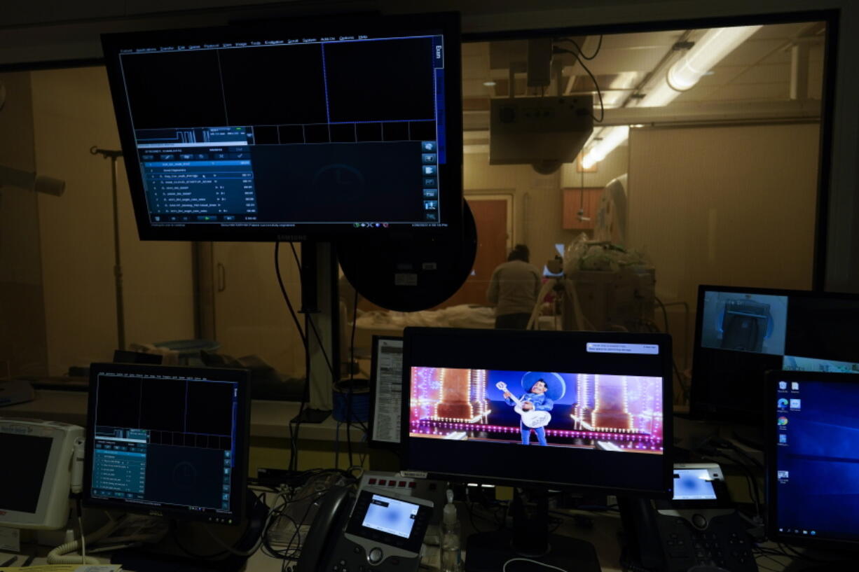 The animated film Coco is shown on a monitor as Charlie Forte, 8, receives an MRI during a long day of testing at Children's National Hospital, in Washington, Wednesday, Jan. 26, 2022. She picked Coco to watch during the MRI. She did not have COVID-19 but her sister, Lexie, 6, did. Both are part of a NIH-funded multi-year study at Children's National Hospital to look at impacts of COVID-19 on children's physical health and quality of life.