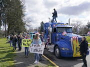 People hold signs as they stand near parked semi-trucks during a protest against COVID-19 vaccine mandates and other issues, Saturday, March 5, 2022, at the Capitol in Olympia, Wash. The trucks were part of a local convoy that traveled to Olympia for the protest. (AP Photo/Ted S.