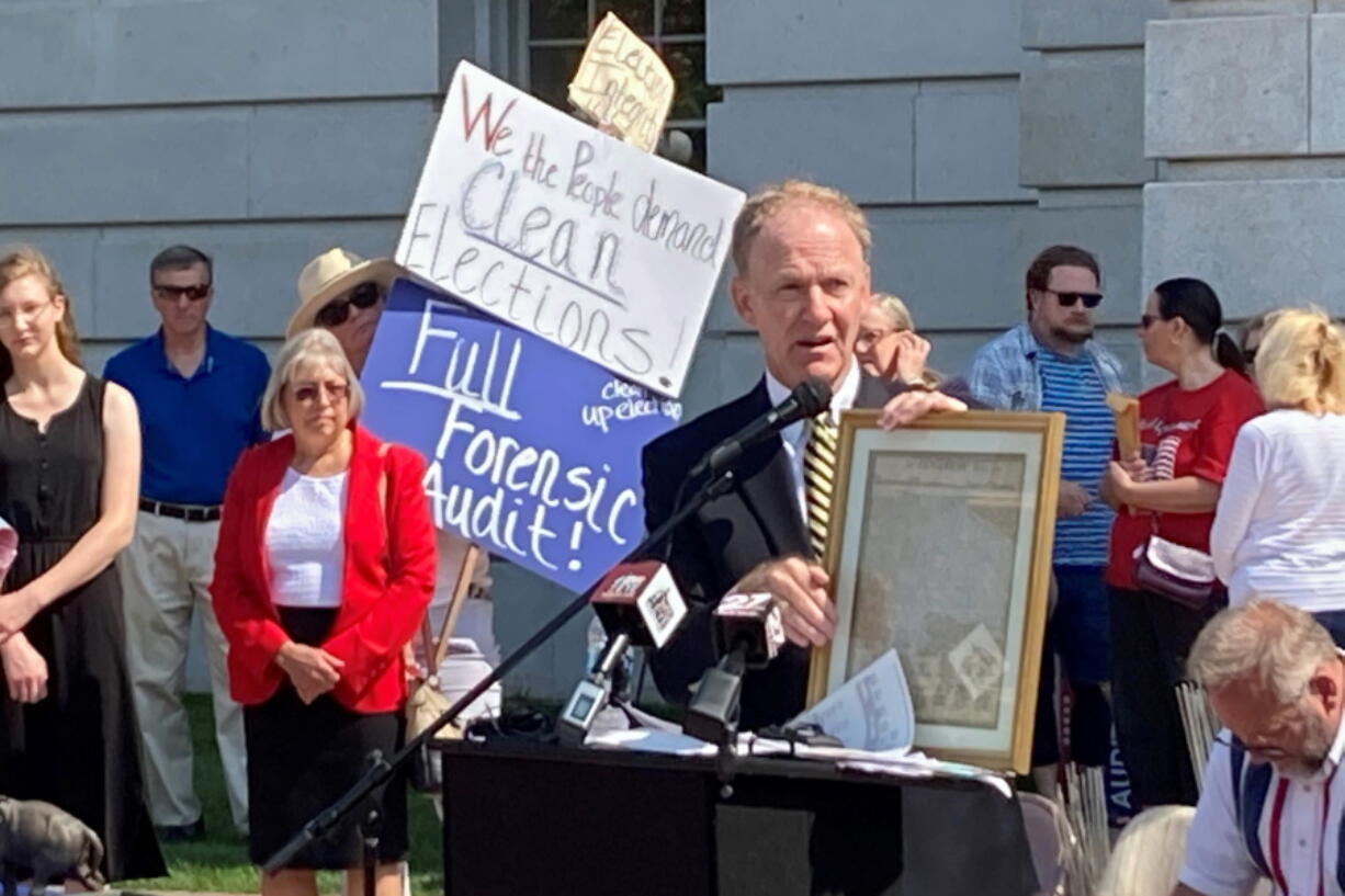 FILE- Jefferson E. Davis, spokesman for a group pushing for a broad review of the 2020 presidential election in Wisconsin, holds up a copy of the Declaration of Independence before leading a group of about 100 people into the state Capitol offices of Republican state leaders asking them to sign subpoenas for access to voting machines, ballots and other election material, on Sept. 10, 2021, in Madison, Wis. The push by Republicans to conduct partisan ballot reviews like the one that unfolded last year in Arizona has spread beyond battleground states disputed by former President Donald Trump. Lawmakers in GOP-dominated state legislative chambers are calling not only for another look at the 2020 presidential election but also the ability to question future contests.