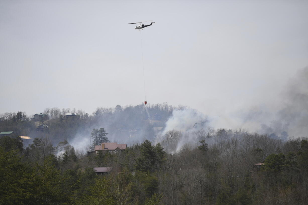 A helicopter dumps water onto a wildfire Wednesday, March 30, 2022, in Sevierville, Tenn.