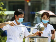 A staff member distributes free traditional Chinese medicine amid a rise in COVID-19 coronavirus cases across the country in Sihong, Suqian city, in China's eastern Jiangsu province, on Aug. 1, 2021.