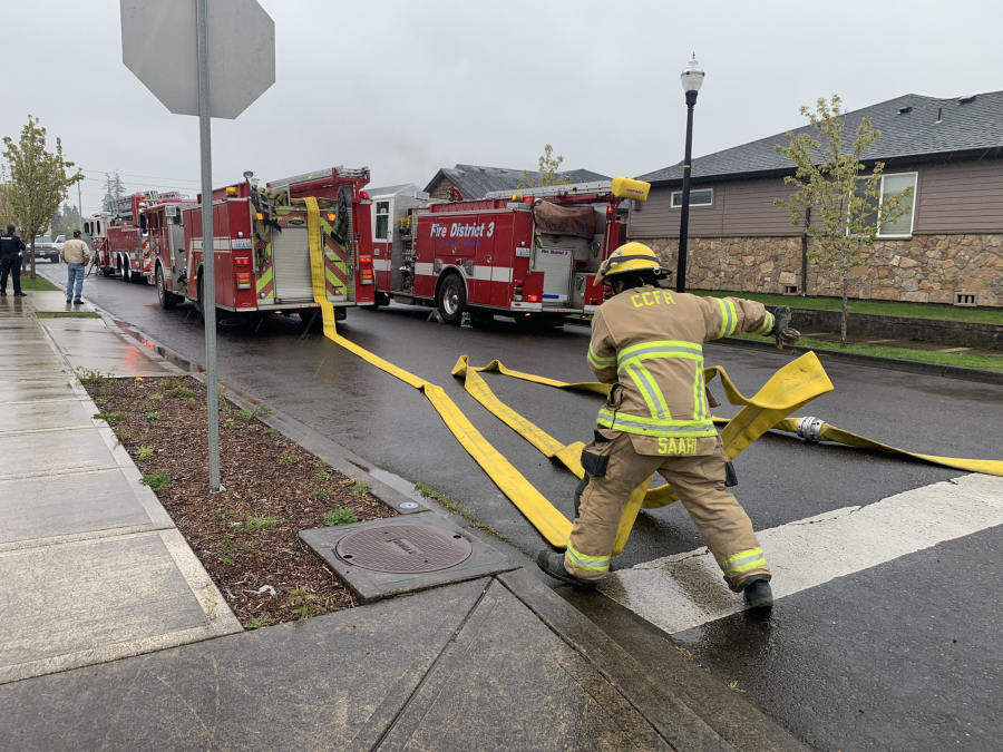 Firefighters work with a hose line at a Battle Ground house fire Monday. A family of five and their pets were displaced.