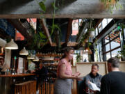 Server Virginia Samsel talks to customers about the drink menu at Light Sleeper on Capitol Hill on Friday, April 1, 2022, in Seattle, Washington.