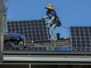 Workers install solar panels on the roof of a home in Granada Hills, California.