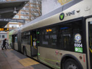 A cyclist boards a C-Tran Vine bus at the Turtle Place Transit Center in downtown Vancouver in February 2021.