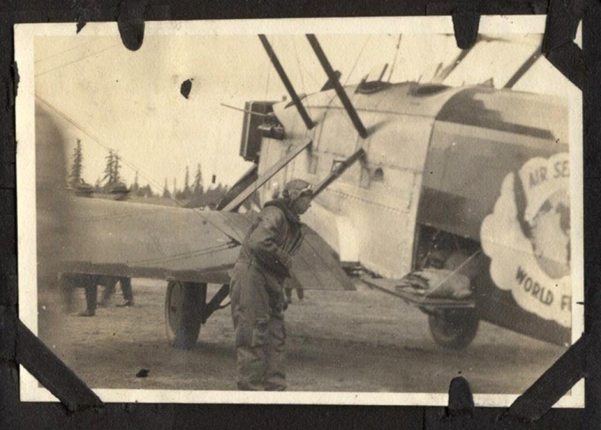 An unidentified airman conducts service on one of four retrofitted Douglas torpedo planes that landed at the Vancouver Barracks Aerodrome (now Pearson Field) in March 1924. A partial world flight logo appears on the plane's body on the right. Four cruisers carrying a pilot and a mechanic started the trip. Two cruisers, but no men, were lost during the 175-day global flight.