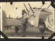 An unidentified airman conducts service on one of four retrofitted Douglas torpedo planes that landed at the Vancouver Barracks Aerodrome (now Pearson Field) in March 1924. A partial world flight logo appears on the plane's body on the right. Four cruisers carrying a pilot and a mechanic started the trip. Two cruisers, but no men, were lost during the 175-day global flight.