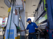 Safety manager Chase Henline of 1-800-Got-Junk? fills up a work vehicle as a nearby sign reflects high fuel prices during a stop at a Shell station in Hazel Dell on Friday morning.