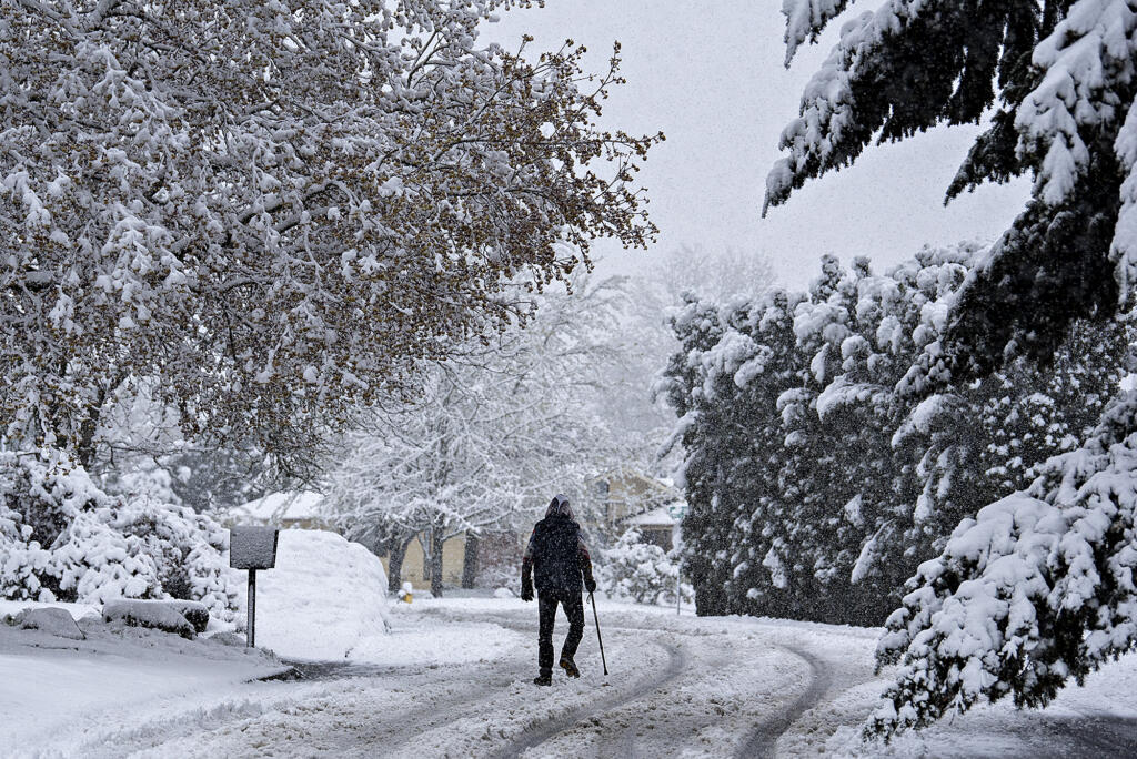 Snowflakes continue to fall as a pedestrian navigates a snowy scene in southeast Vancouver on Monday morning, April 11, 2022.