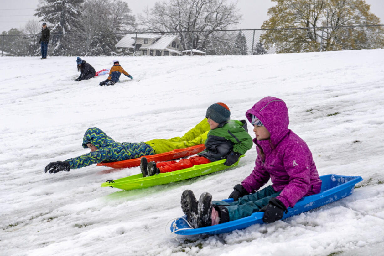 Emmaus Brownfield, 11, of Vancouver, left, races his siblings Alastair, 6, and Amira, 9, at the Franklin Elementary School sledding hill Monday.